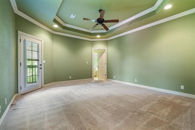 spare room with ceiling fan, a raised ceiling, light colored carpet, and crown molding