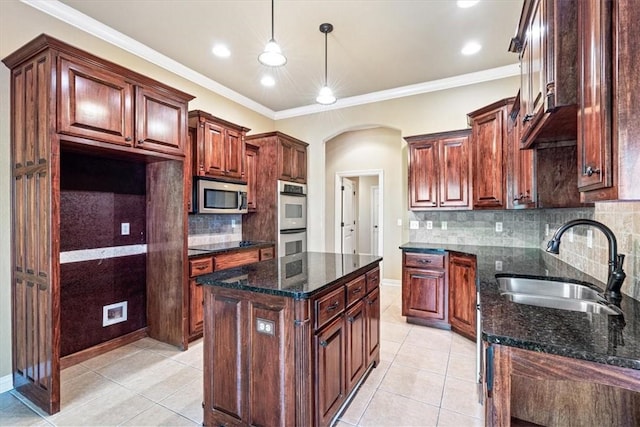 kitchen with dark stone counters, multiple ovens, sink, pendant lighting, and a kitchen island