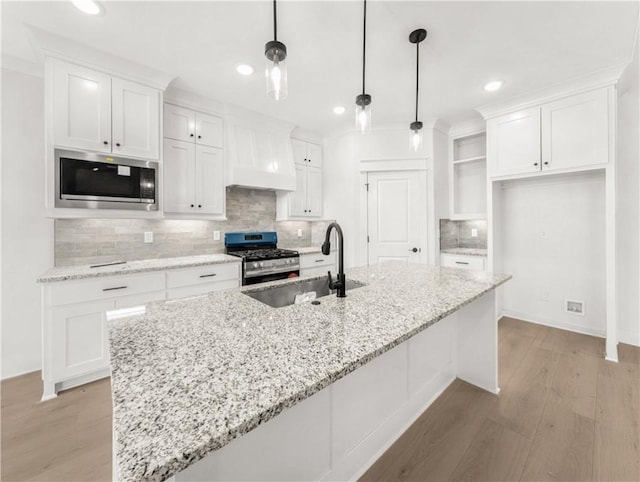 kitchen featuring appliances with stainless steel finishes, white cabinetry, backsplash, and a sink