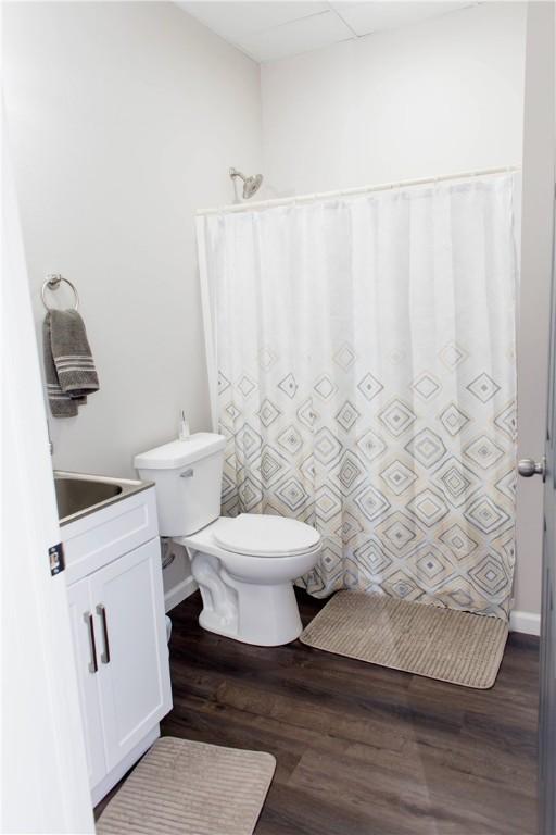 full bathroom with curtained shower, vanity, toilet, and wood finished floors