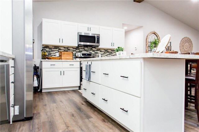 kitchen featuring white cabinetry, lofted ceiling, backsplash, and dark wood-type flooring