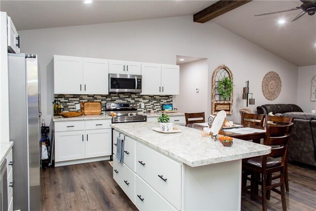 kitchen with a kitchen island, ceiling fan, dark hardwood / wood-style floors, stainless steel appliances, and lofted ceiling with beams