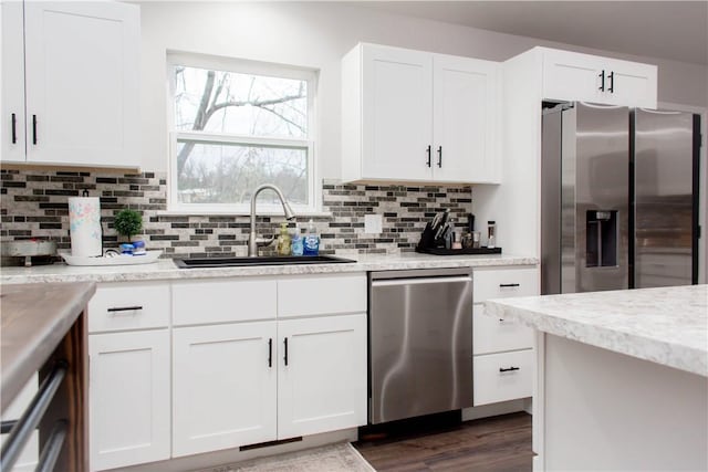 kitchen with stainless steel appliances, tasteful backsplash, dark wood-type flooring, white cabinetry, and a sink