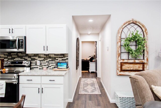 kitchen featuring white cabinetry, tasteful backsplash, light stone counters, dark hardwood / wood-style floors, and appliances with stainless steel finishes