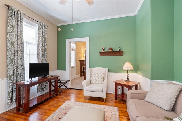 living room with hardwood / wood-style flooring, crown molding, and ceiling fan