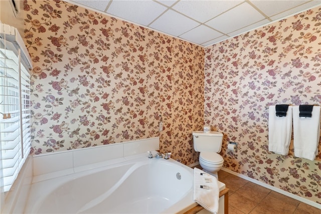 bathroom featuring a bathing tub, tile patterned flooring, a drop ceiling, and toilet