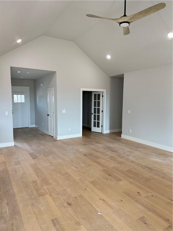 unfurnished living room featuring ceiling fan, vaulted ceiling, and light hardwood / wood-style floors