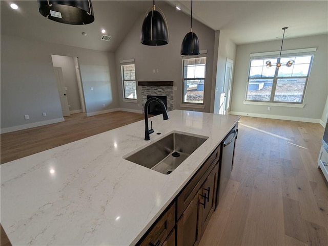 kitchen featuring pendant lighting, light stone countertops, sink, and dishwasher