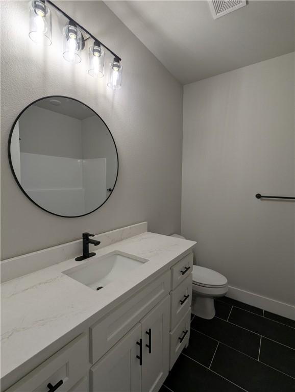 bathroom featuring vanity, tile patterned floors, and toilet