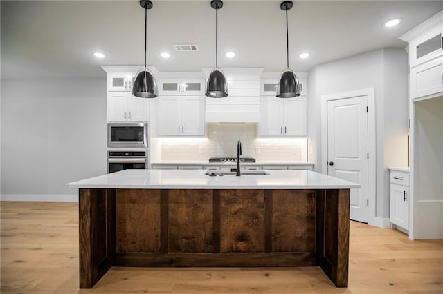 7843 Range Ave, Springdale, AR 72762 - kitchen featuring oven, built in microwave, a sink, light wood finished floors, and a center island with sink