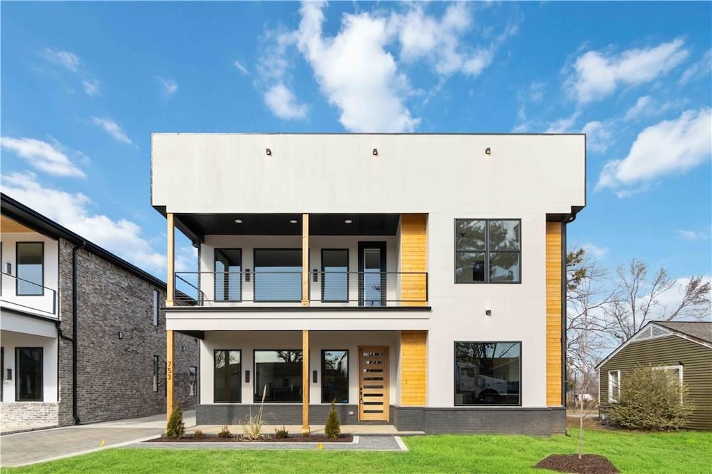 rear view of house with a balcony and a yard