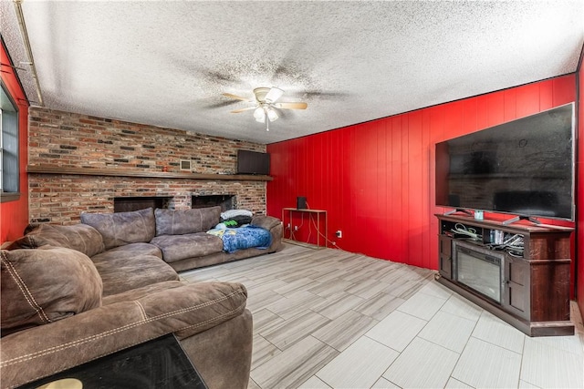 living room with a textured ceiling, ceiling fan, a fireplace, and wood walls