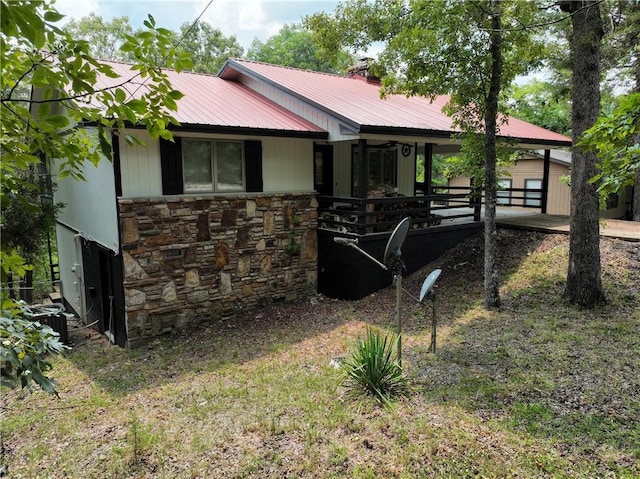 view of property exterior with metal roof, stone siding, and a chimney