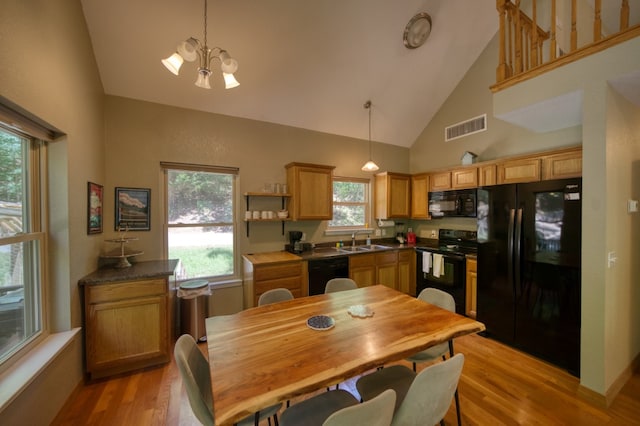 dining space with sink, light wood-type flooring, high vaulted ceiling, and a chandelier