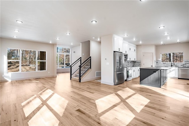 kitchen featuring a kitchen island, white cabinets, stainless steel appliances, and decorative backsplash