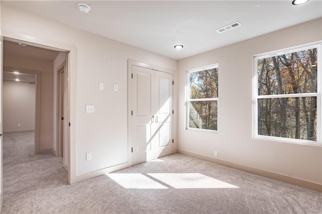 unfurnished bedroom featuring baseboards, visible vents, and light colored carpet