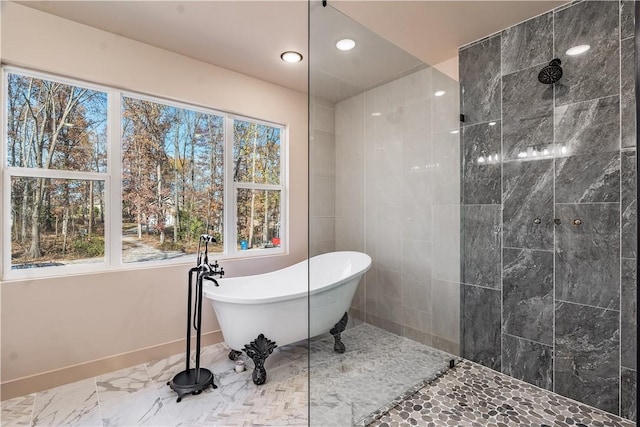 bathroom featuring a healthy amount of sunlight, a soaking tub, marble finish floor, and walk in shower