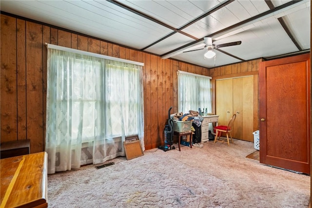 interior space featuring ceiling fan and wood walls