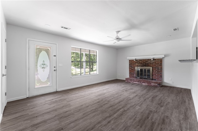 unfurnished living room featuring dark hardwood / wood-style floors, ceiling fan, and a brick fireplace