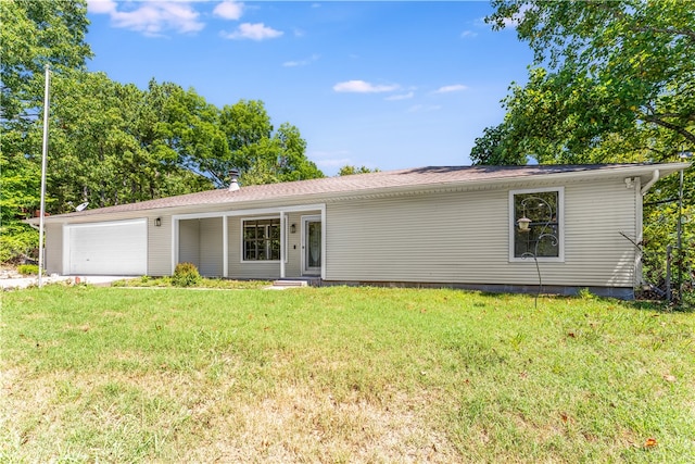 rear view of house featuring a garage and a yard