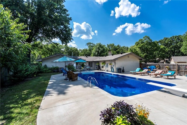 view of swimming pool featuring a patio area, fence, and a diving board