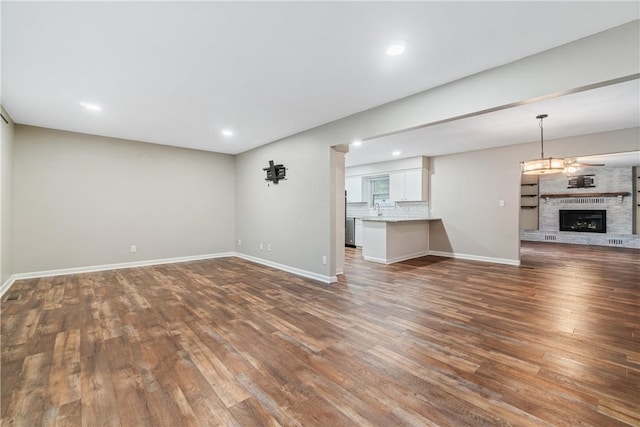 unfurnished living room featuring sink, dark hardwood / wood-style flooring, and a brick fireplace