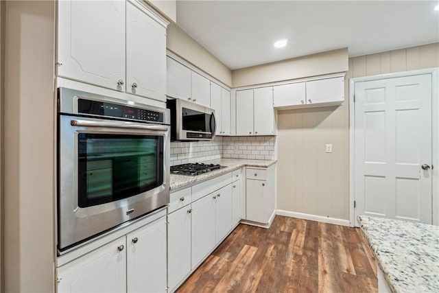 kitchen featuring dark hardwood / wood-style flooring, tasteful backsplash, light stone counters, stainless steel appliances, and white cabinetry