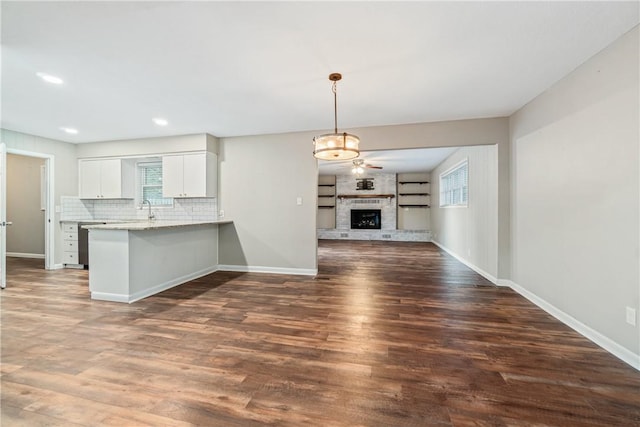 kitchen with white cabinetry, light stone countertops, a healthy amount of sunlight, kitchen peninsula, and pendant lighting