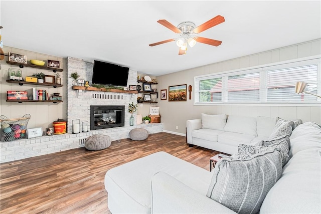 living room with hardwood / wood-style flooring, ceiling fan, and a fireplace