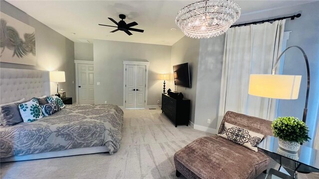 carpeted bedroom with ceiling fan with notable chandelier