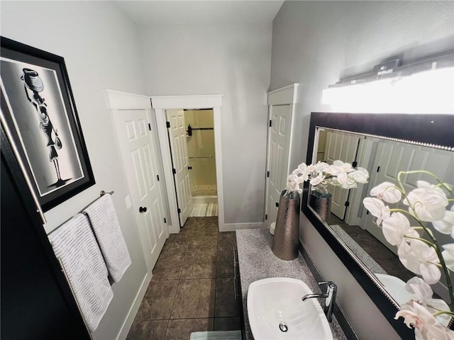 bathroom featuring a closet, a sink, and baseboards