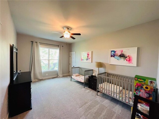 carpeted bedroom with a nursery area and ceiling fan