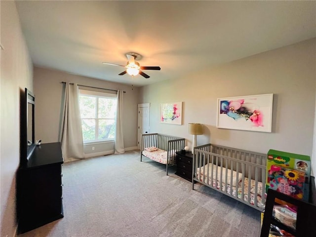 bedroom with ceiling fan, a crib, carpet flooring, and baseboards