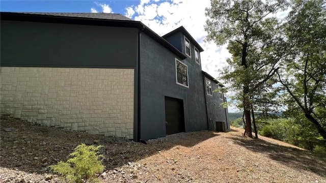 view of home's exterior featuring driveway, a garage, cooling unit, and stucco siding