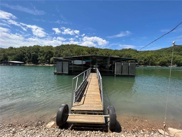 view of dock with a water view and a forest view