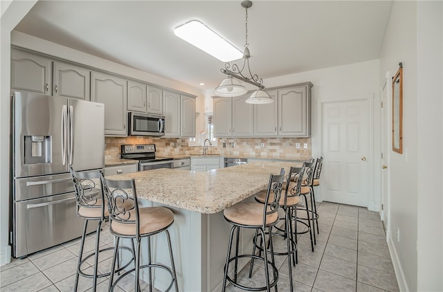 kitchen with stainless steel appliances, sink, a kitchen island, and light tile patterned floors