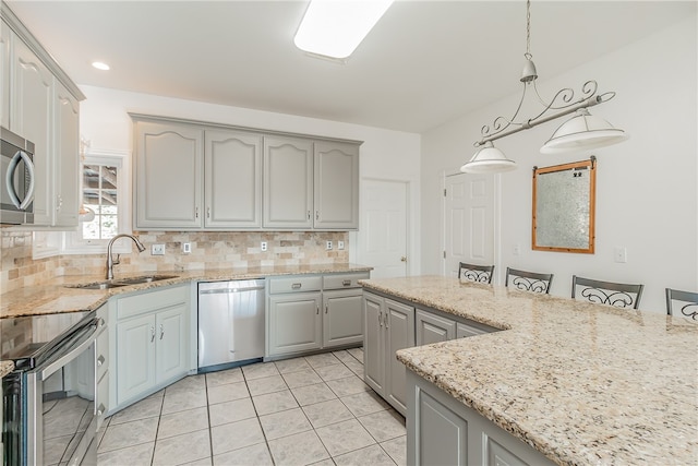 kitchen featuring sink, gray cabinetry, pendant lighting, stainless steel appliances, and decorative backsplash