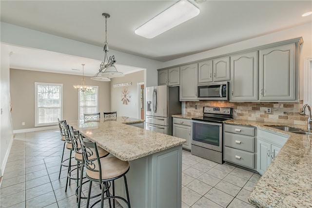 kitchen with gray cabinets, appliances with stainless steel finishes, tasteful backsplash, sink, and a center island