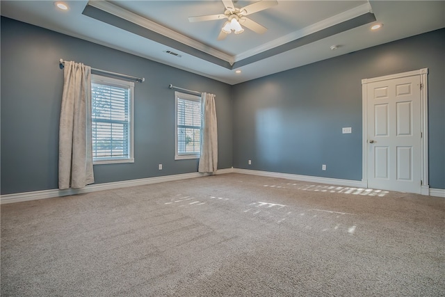 carpeted spare room with crown molding, a tray ceiling, and ceiling fan