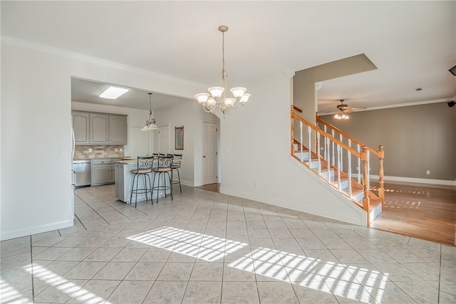 unfurnished living room featuring ceiling fan with notable chandelier, ornamental molding, and light tile patterned flooring