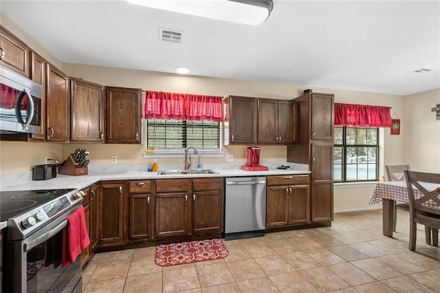 kitchen with sink, light tile patterned flooring, and stainless steel appliances