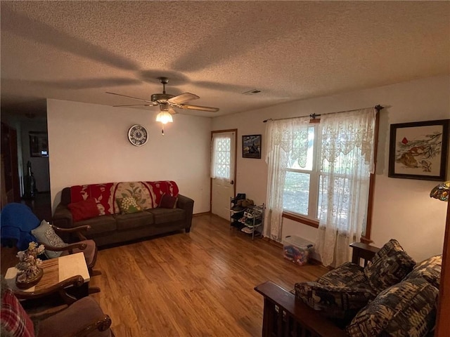 living room with ceiling fan, wood-type flooring, and a textured ceiling