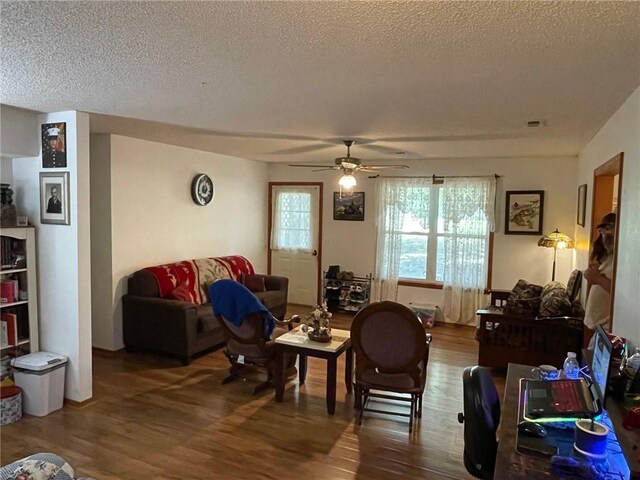 living room with a textured ceiling, hardwood / wood-style floors, and ceiling fan