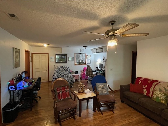 living room featuring wood-type flooring, ceiling fan, and a textured ceiling