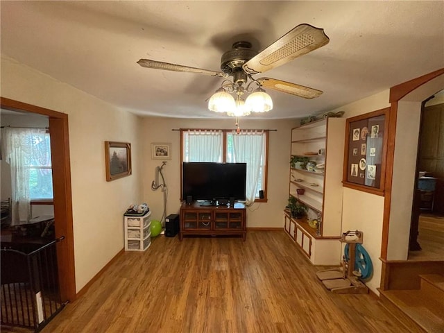 living room featuring ceiling fan, wood-type flooring, and a wealth of natural light