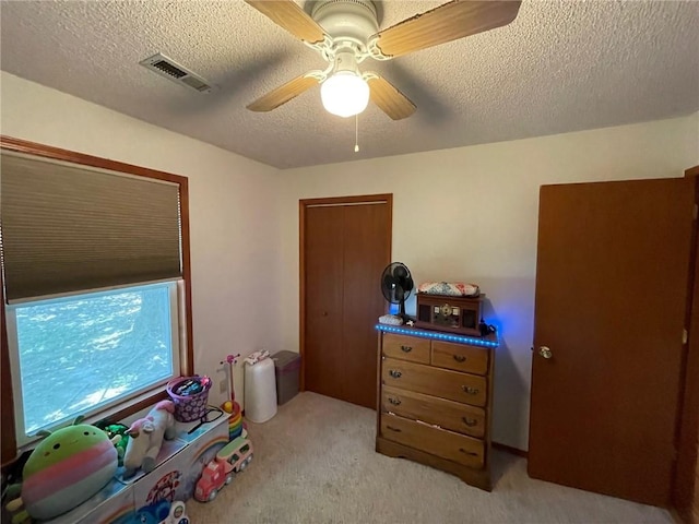 interior space with light carpet, ceiling fan, and a textured ceiling