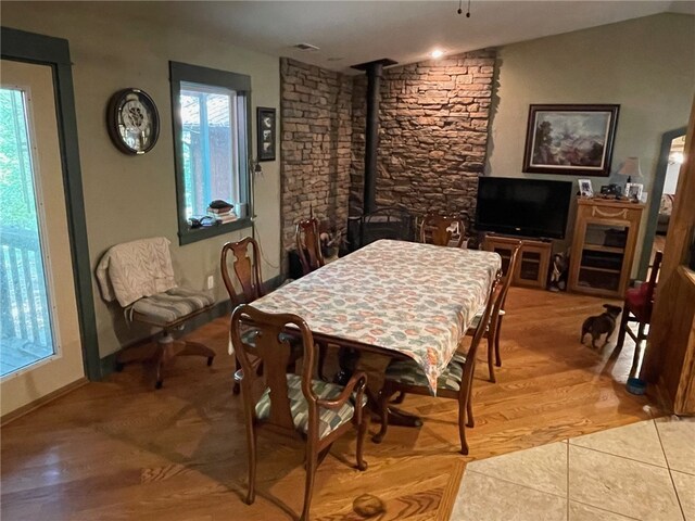 dining room featuring light hardwood / wood-style flooring, lofted ceiling, and a wood stove