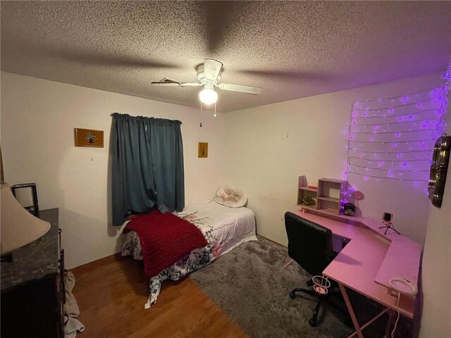 bedroom with a textured ceiling, hardwood / wood-style floors, and ceiling fan