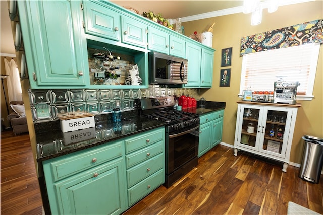 kitchen with stainless steel appliances, ornamental molding, dark hardwood / wood-style flooring, and dark stone counters