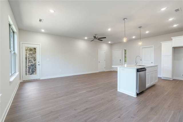 kitchen featuring white cabinetry, hanging light fixtures, light wood-type flooring, dishwasher, and a kitchen island with sink